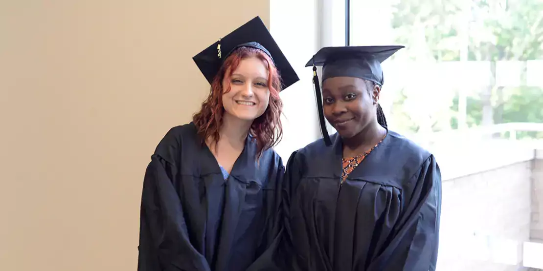 Two people wearing a graduation cap and gown