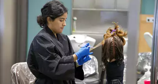 A woman working on a head of hair