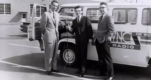Three men in front of a radio broadcasting van