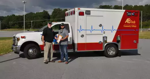 Two men in front of Woodfin's new ambulance
