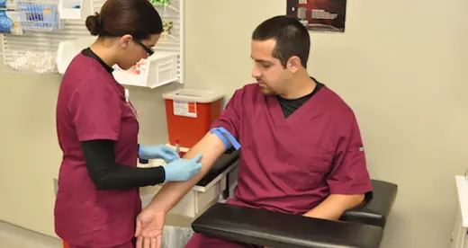 Woman drawing blood from the arm of a man