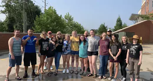 A group of wet students standing on a concrete surface. 