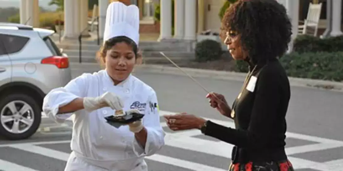 Culinary student handing Leronica Casey some food at Autumn In Asheville