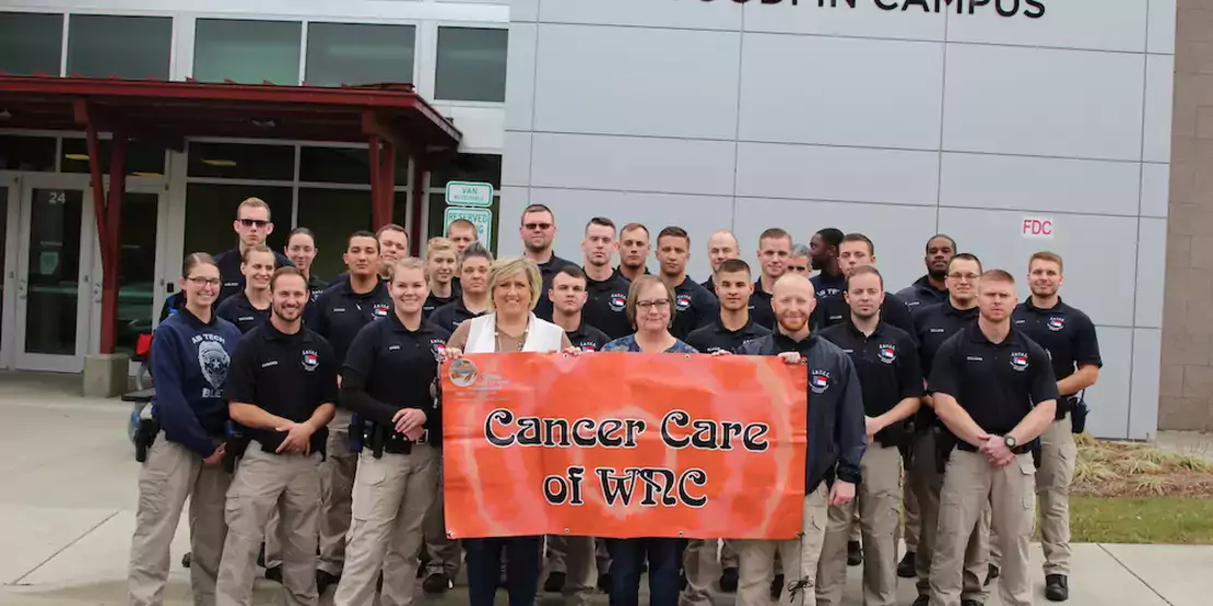 28 students and two women holding a banner reading Cancer Care of WNC