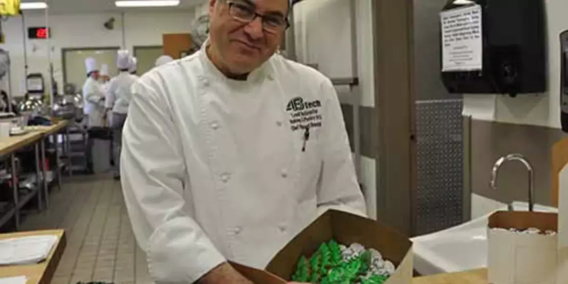 Chef Vince Donatelli with a box of cookies shaped like pine trees