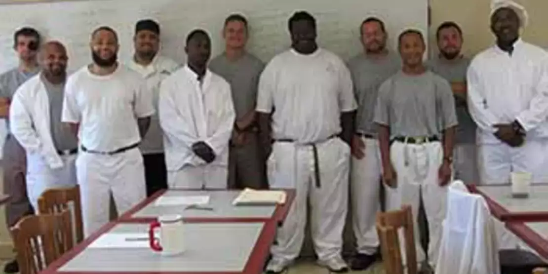 Twelve chef inmates lined up with the teaching assistant wearing a white hat.