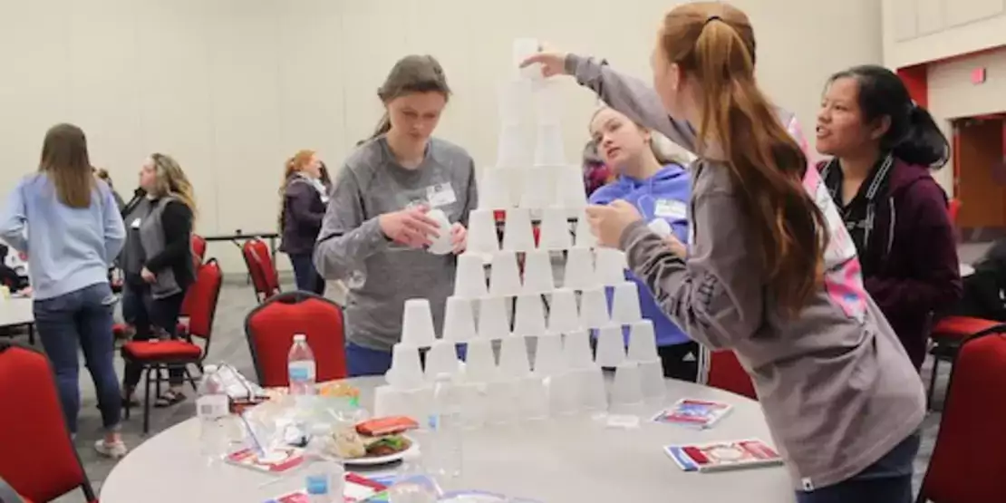 Women stacking cups in a pyramid