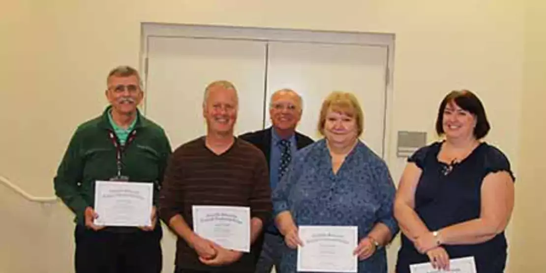 Five people standing with certificates
