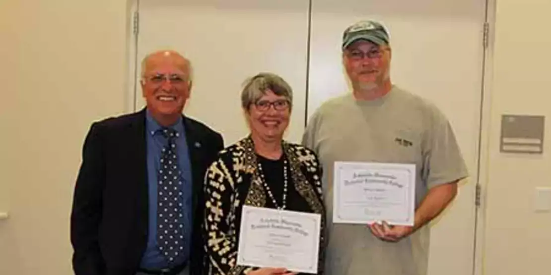 Three people standing with certificates