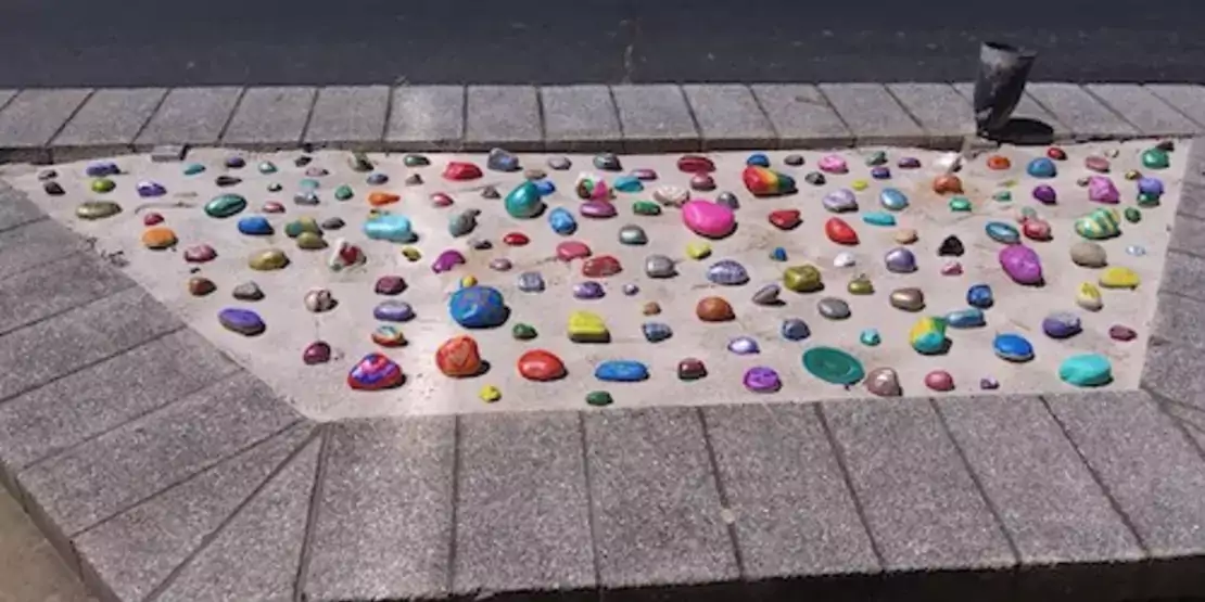 Rocks with positive messages laid in sand pit.