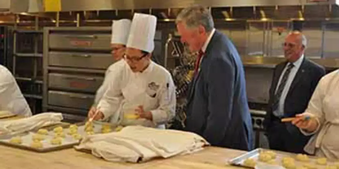 Mark Meadows at counter talking to a  Baking and Pastry Arts student