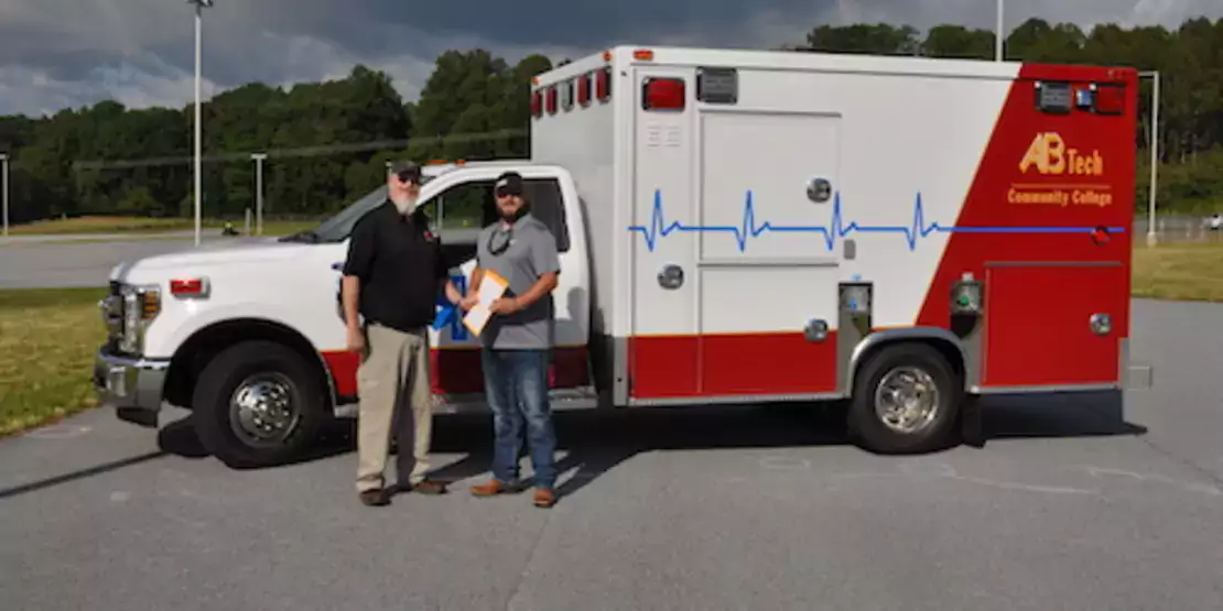 Two men in front of Woodfin's new ambulance