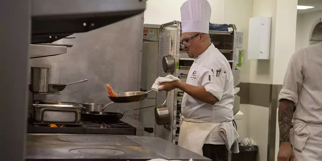 Chef with frying pan in front of stove