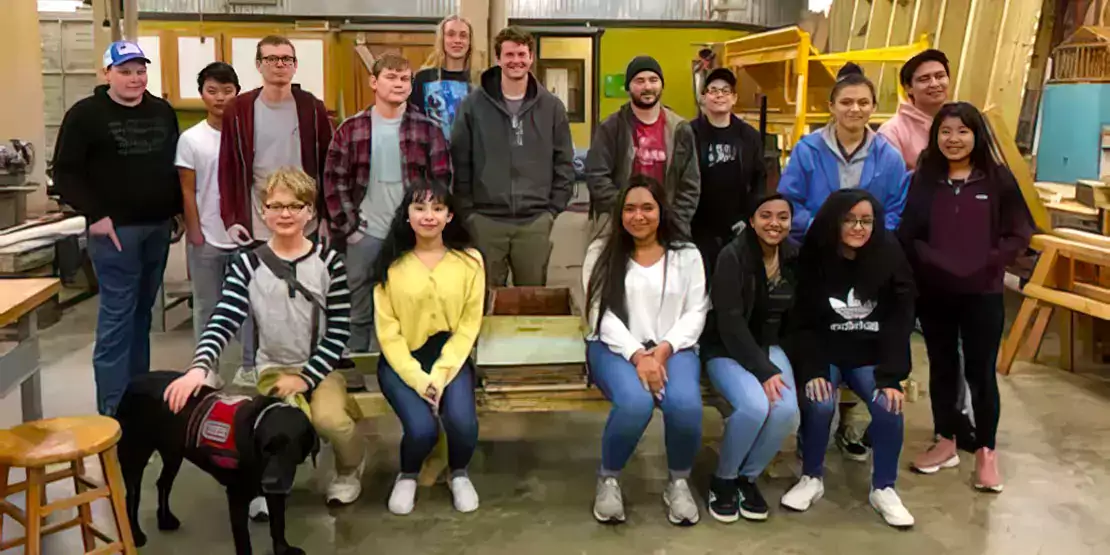 A group of construction students with a newly constructed bee bench